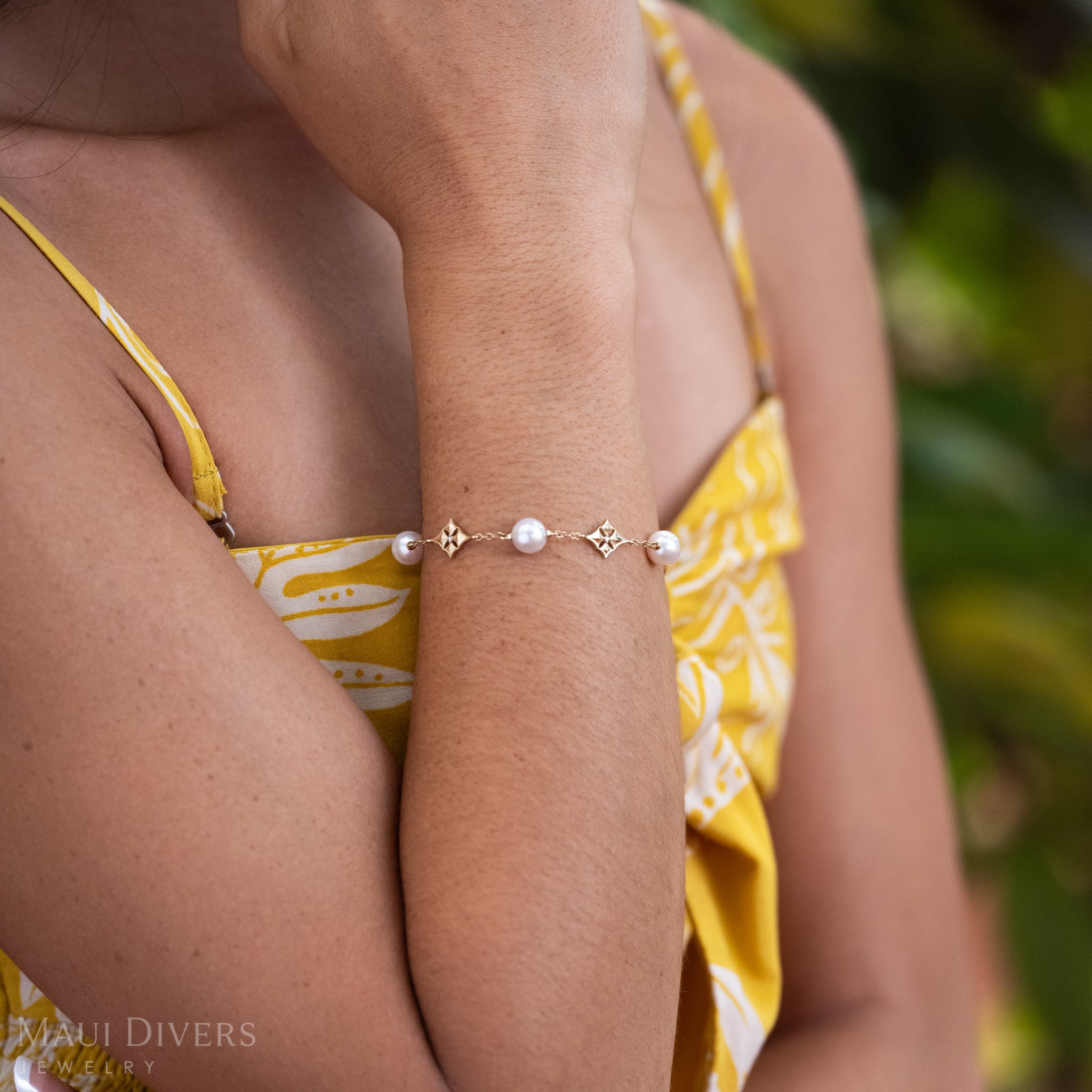 Close up of a woman wearing 14k Gold Hawaiian Quilted Star Bracelet with White Akoya Pearls and Diamonds around her wrist.