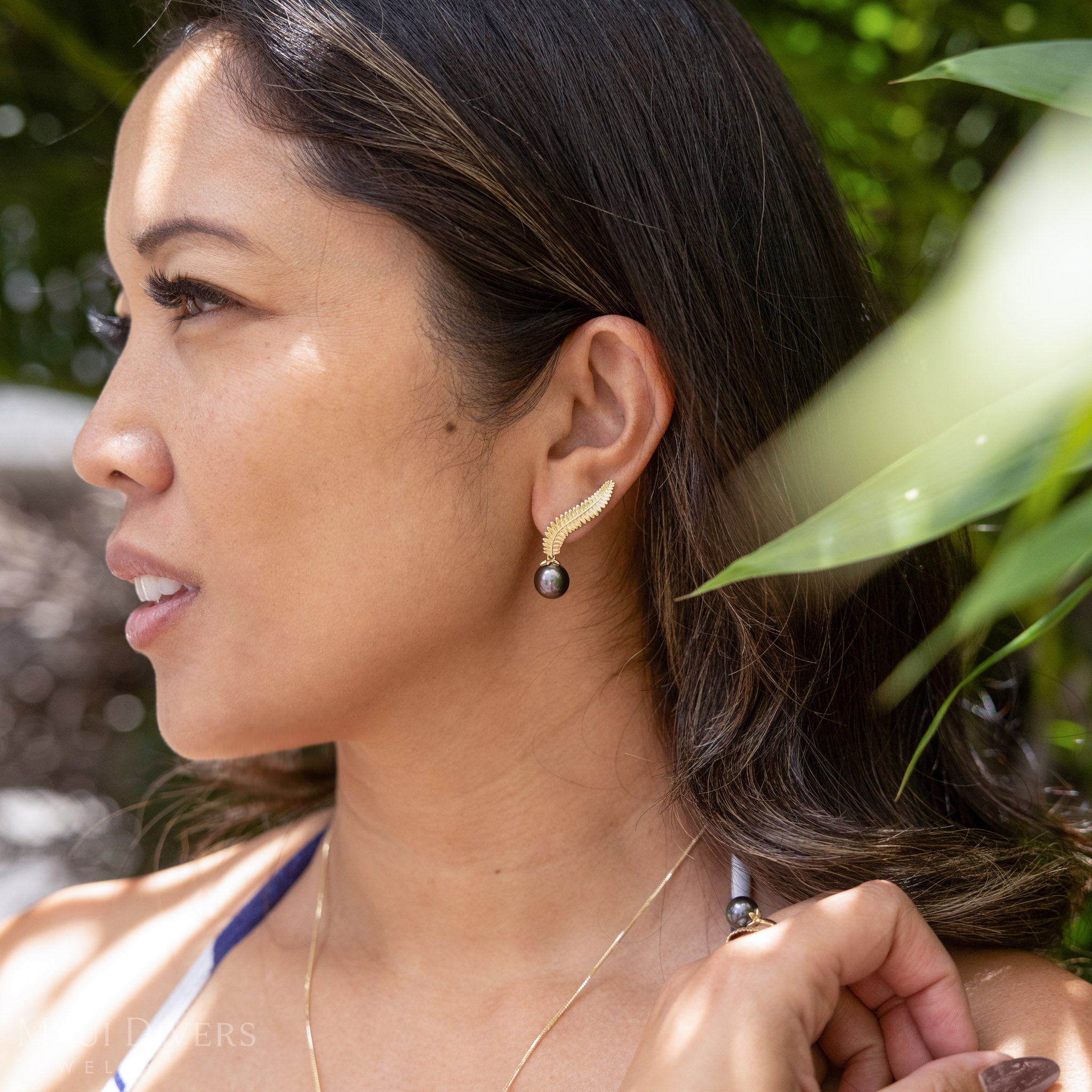 A woman wearing the kupukupu fern Tahitian black pearl climber earring
