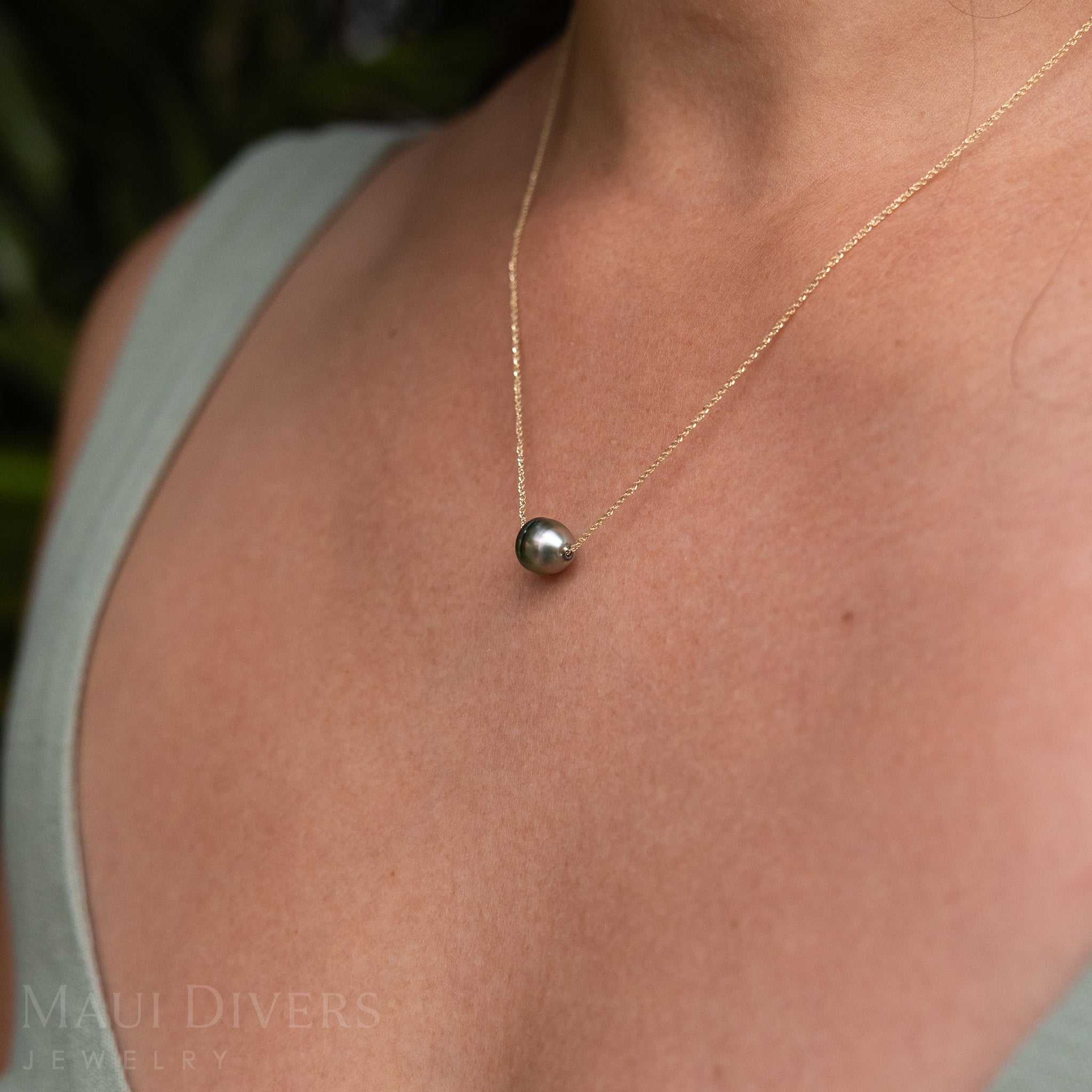 Close-up of an Adjustable Tahitian Black Pearl Necklace in 14k yellow gold worn on a neck