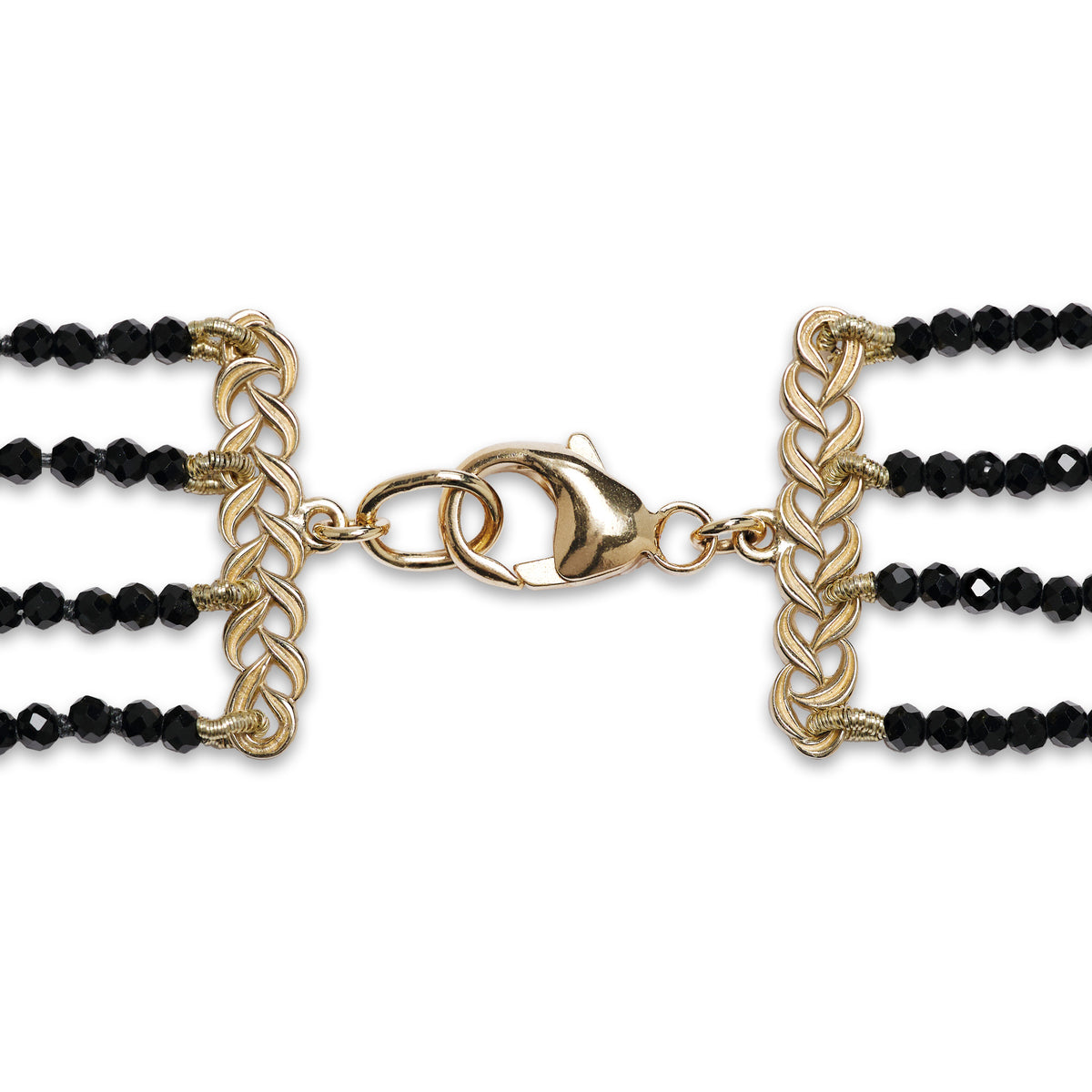Detail shot of a gold lobster claw clasp with a black spinel necklace attached on each side with gold maile leaves, shown on a white background