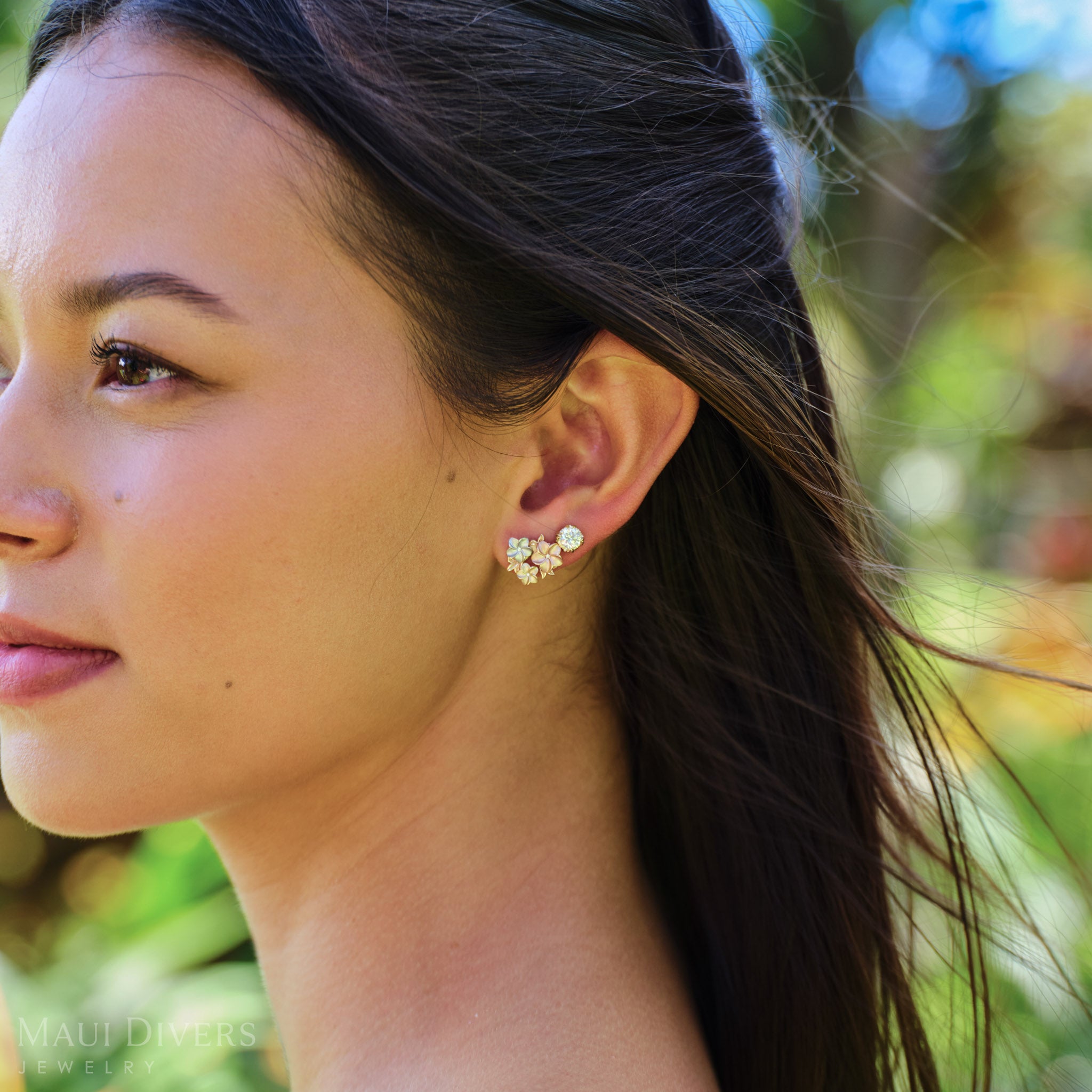 Side close-up view of a woman wearing a Hidden Hawaiʻi Maile Earring in 14k Yellow Gold with Lab Grown Diamond and a Plumeria Earring in Tri Color Gold with Diamonds on her left ear