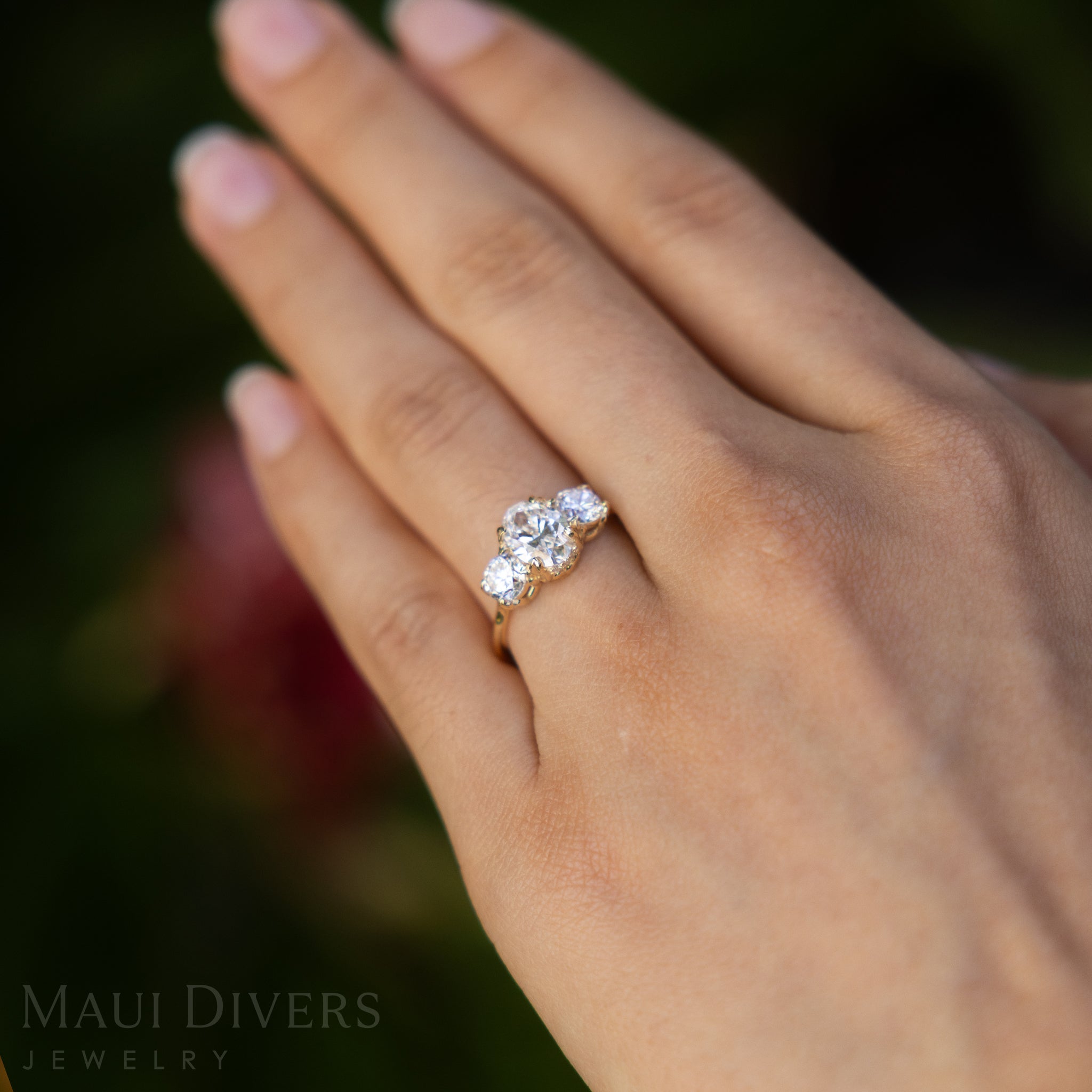 Hand wearing a lab-grown diamond ring with a blurred natural background