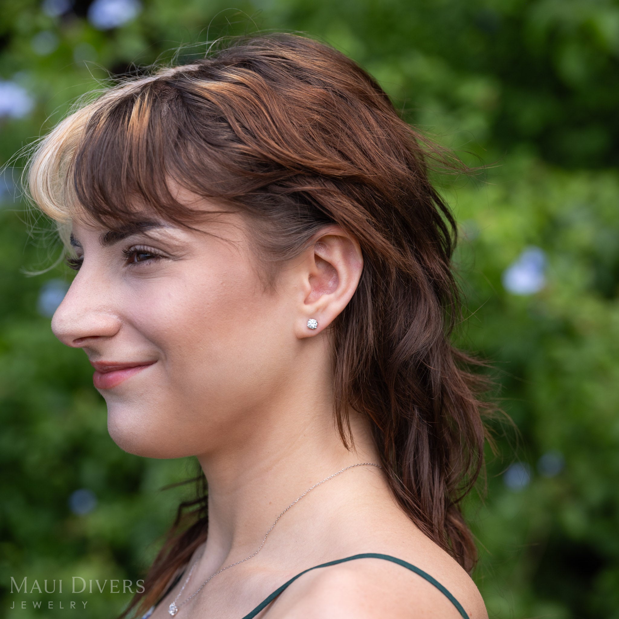 A profile of a woman wearing a lab-grown diamond maile leaf stud earrings in 14k white gold