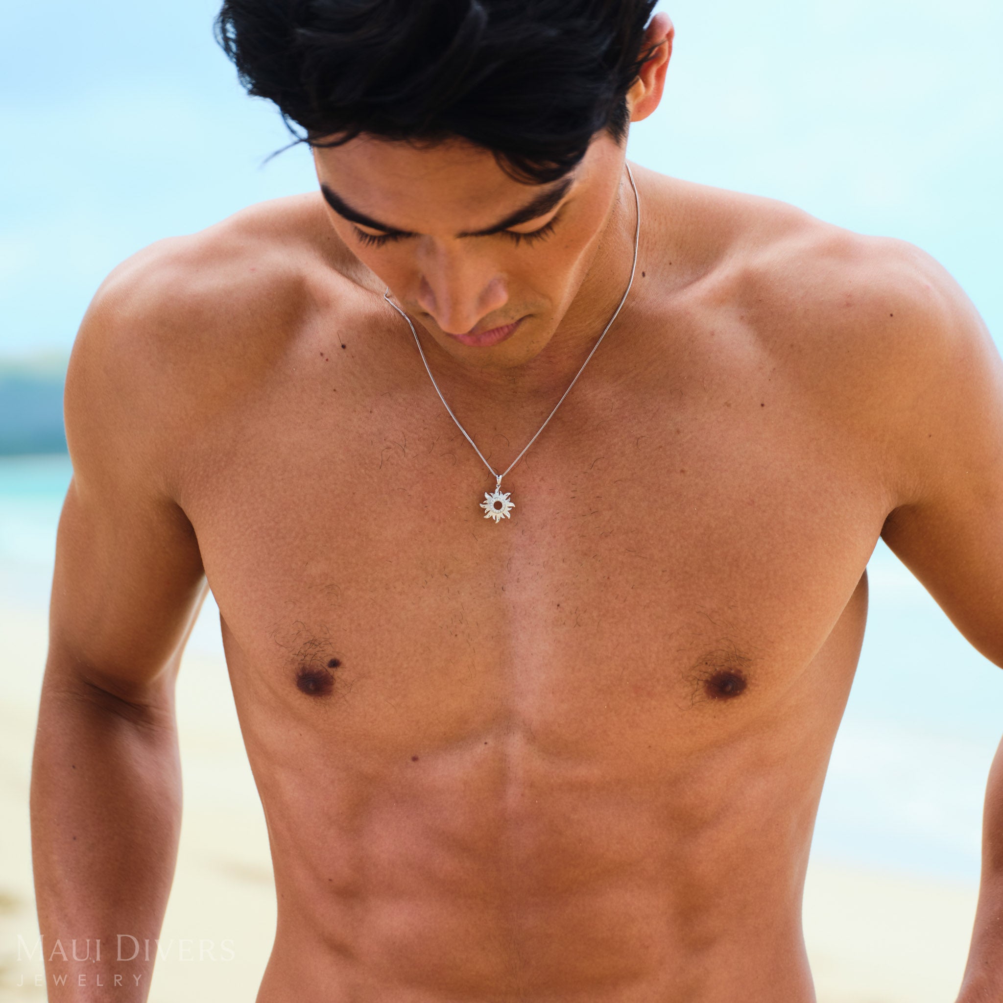 Man wearing a white gold sun pendant with diamonds on beach