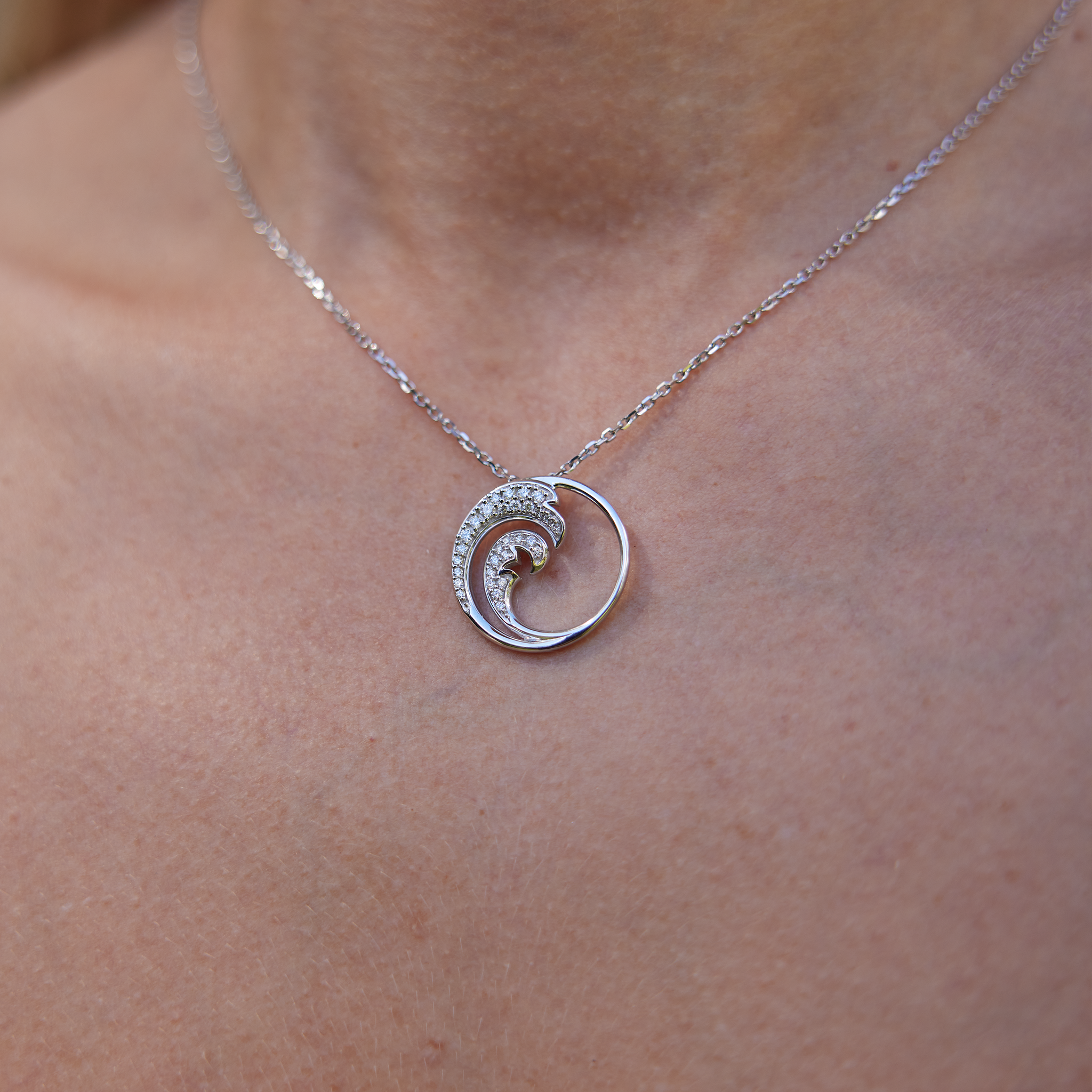 Close up of Nalu Pendant in White Gold with Diamonds - 22mm on womanʻs neckline