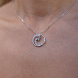 Close up of Nalu Pendant in White Gold with Diamonds - 22mm on womanʻs neckline