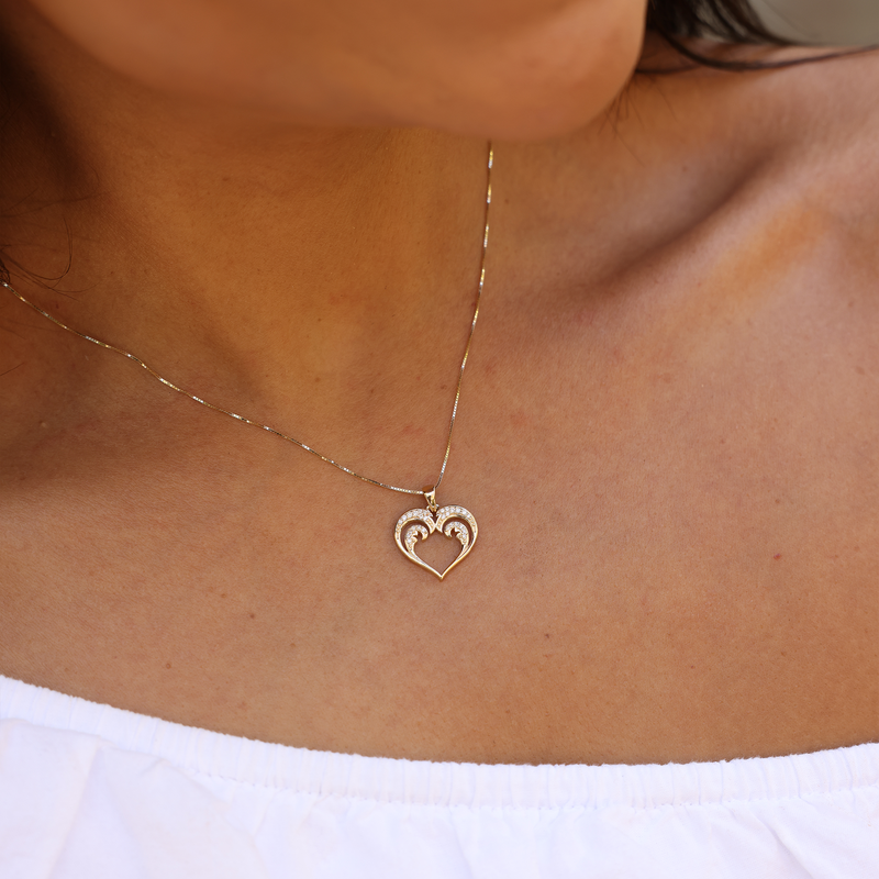 A woman's chest with a Nalu Heart Pendant in Gold with Diamonds - 15mm - Maui Divers Jewelry