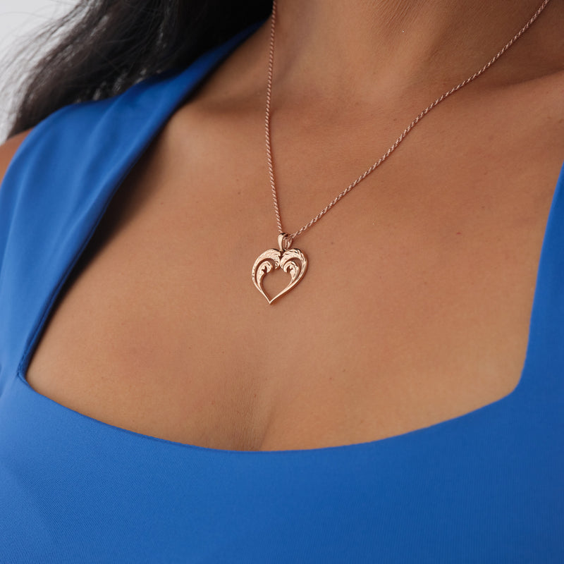 A woman's chest with a Nalu Heart Pendant in Rose Gold - 20mm - Maui Divers Jewelry