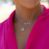 a woman wearing a pink dress and a 0.8mm Baby Rope Chain in White Gold necklace by Maui Divers Jewelry with a turtle on it.