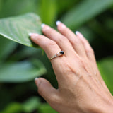 Woman wearing Maile Leaf Black Coral Ring in Gold with leafy background