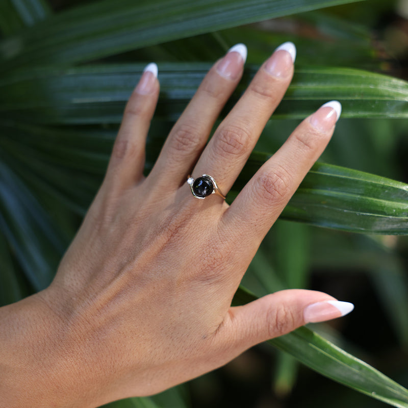 woman's hand touching leaves with Black Coral Ring in Gold with Diamonds