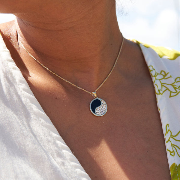 close up of womanʻs neckline wearing Yin Yang Black Coral Pendant in Gold with Diamonds - 18.5mm
