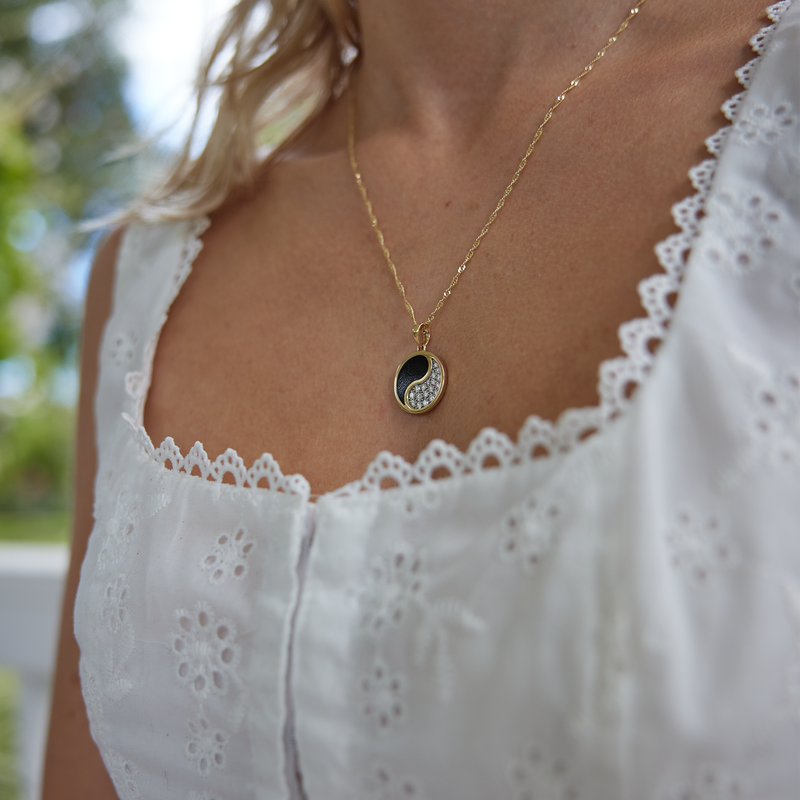 woman wearing a white blouse with Yin Yang Black Coral Pendant in Gold with Diamonds - 18.5mm on a singapore chain