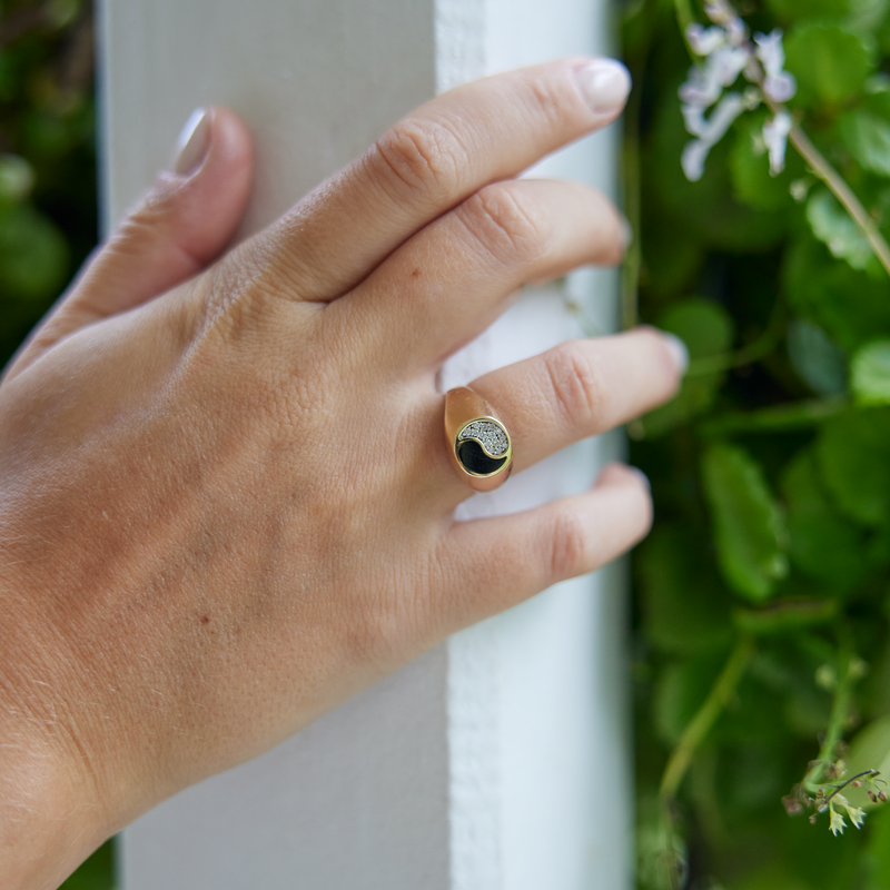 Womanʻs hand wearing Yin Yang Black Coral Ring in Gold with Diamonds - 10mm with nature background