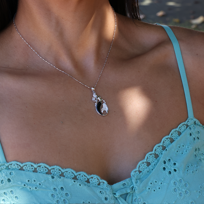 A woman's chest with a Sealife Mermaid Black Coral Pendant in White Gold with Diamonds - 30mm - Maui Divers Jewelry