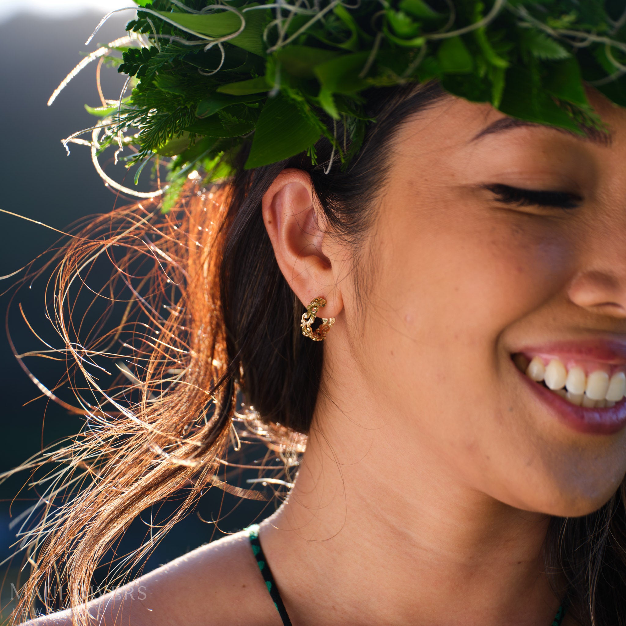 Smiling woman in a leafy headpiece wearing a Living Heirloom hoop earring in 14k yellow gold with diamond accents