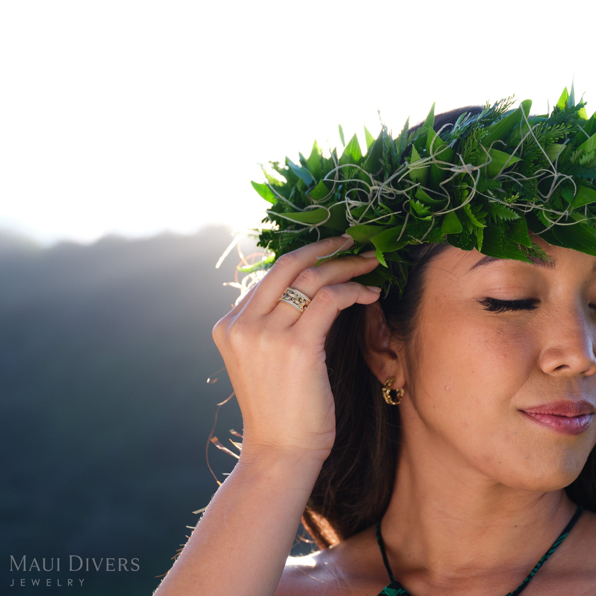 Woman in a leafy headpiece wearing a Living Heirloom designed ring with diamonds in 14k yellow gold against a blurred neutral background