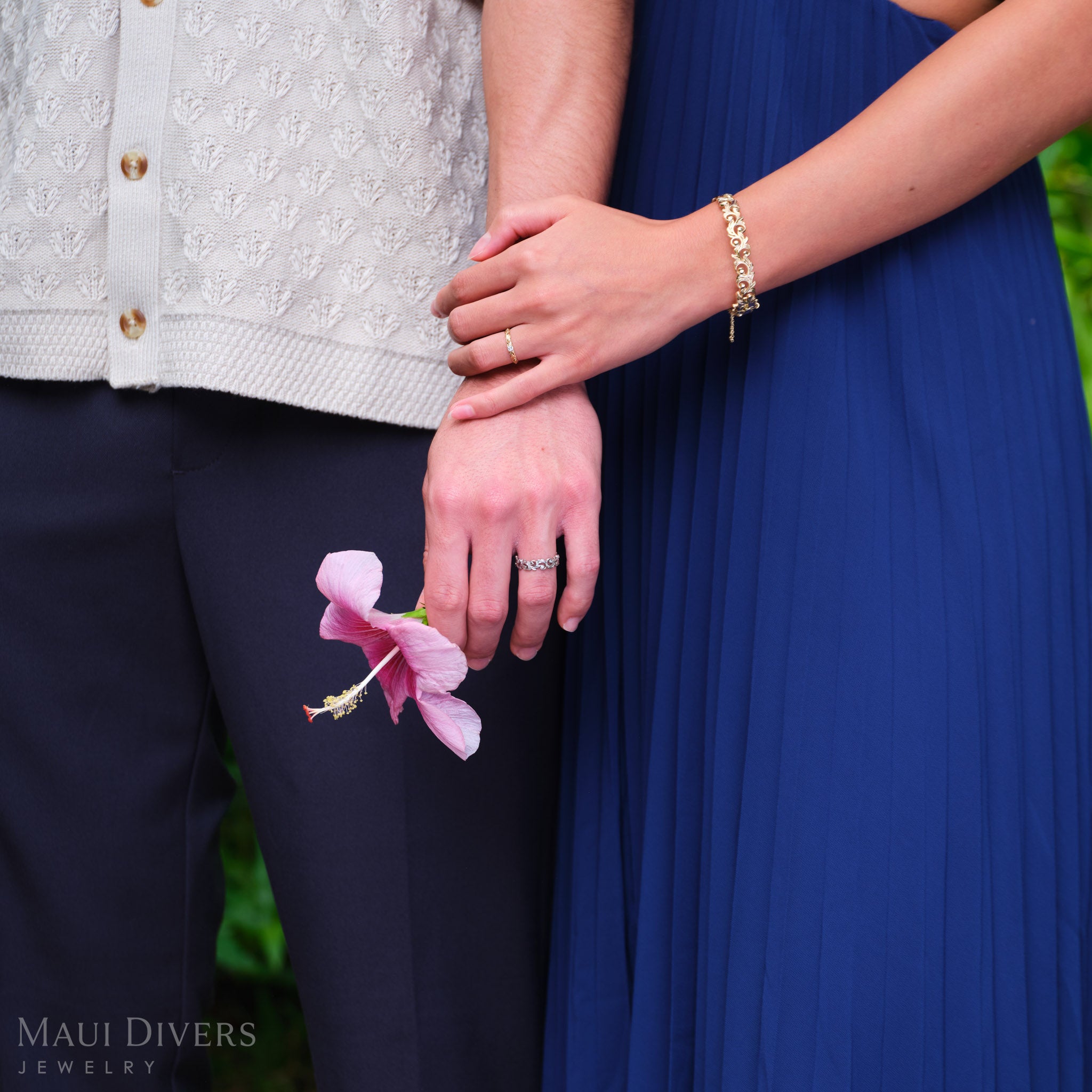 Close-up of a woman wearing a Living Heirloom Ring in 14k yellow gold with a diamond on her ring finger, holding a man's arm down by his side