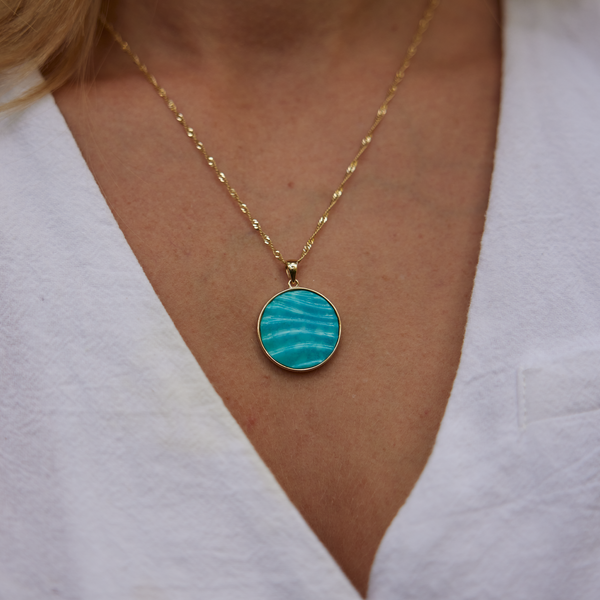 Close up of womanʻs neckline wearing Hawaiian Moments Ocean Sand Pendant in Gold with Turquoise - 22mm