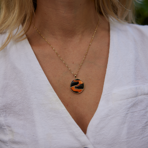 Lava Flow Black Coral and Spiny Oyster Pendant in Gold on womanʻs neckline