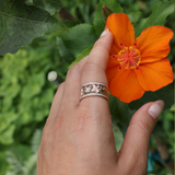 A woman's hand with a Hawaiian Heirloom Plumeria Ring in Rose Gold with Diamonds touching a flower - Maui Divers Jewelry