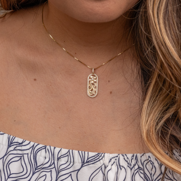 Close up of womanʻs neckline wearing Hawaiian Heirloom Plumeria Pendant in Gold with Diamonds