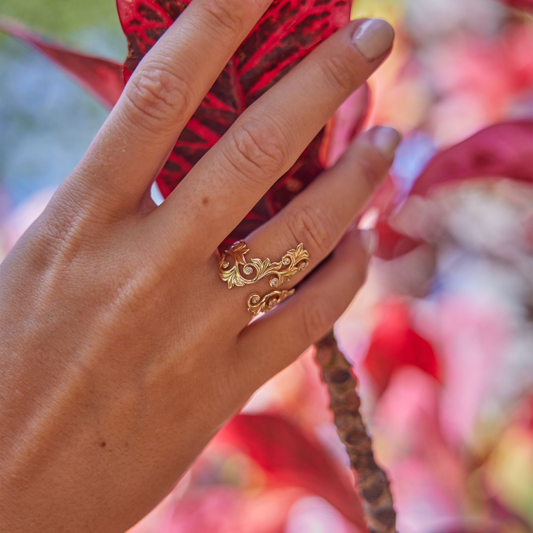 Woman wearing Living Heirloom Scroll Ring in Gold with Diamonds as she touches a red leaf