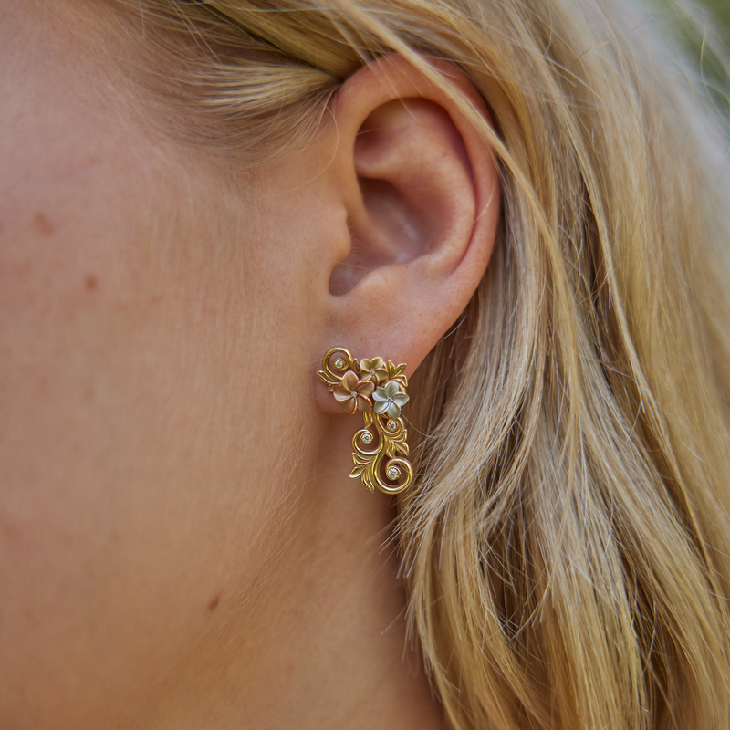 Close up of womanʻs left ear wearing Living Heirloom Plumeria Earrings in Tri Color Gold with Diamonds - 25mm