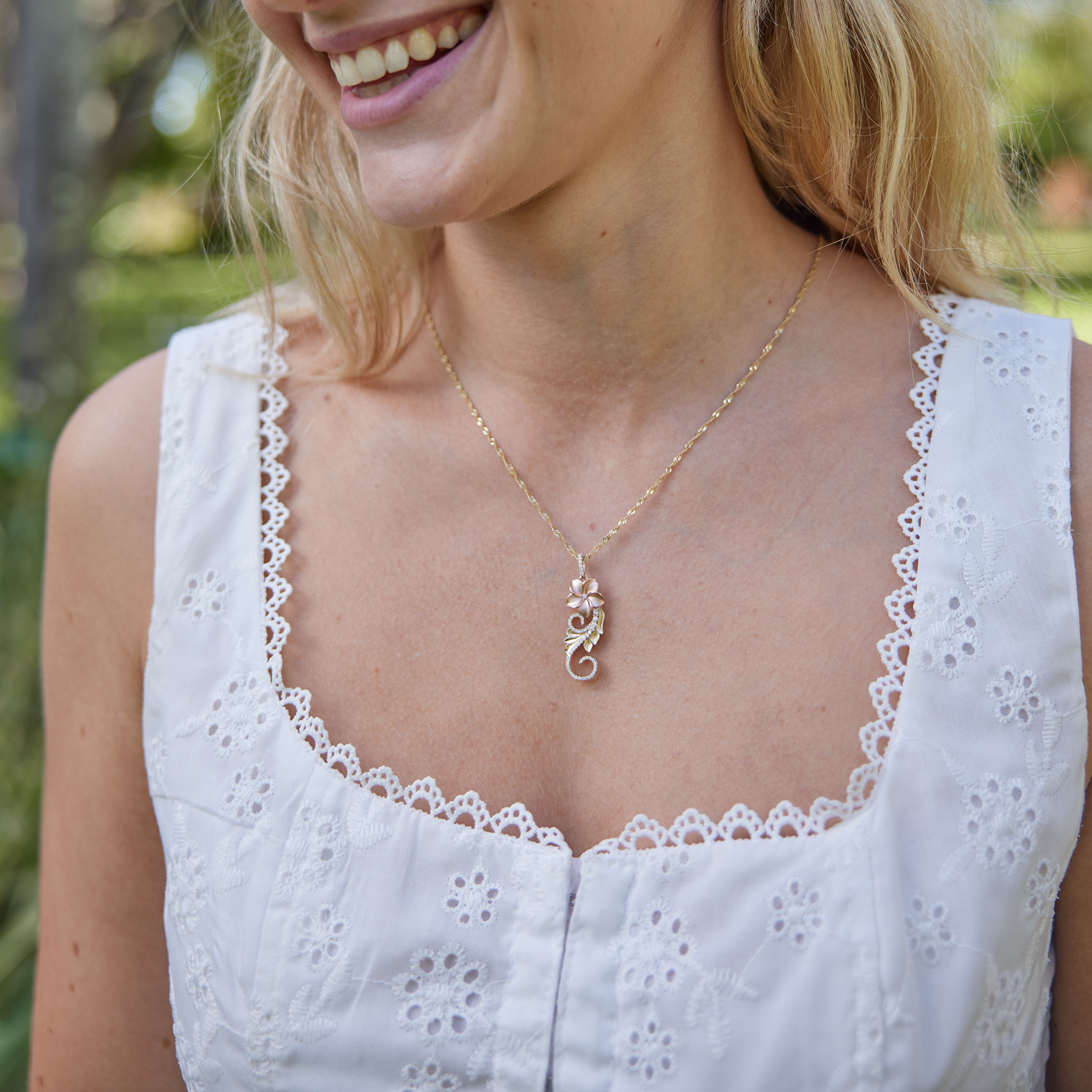 neckline showcasing Hawaiian Heirloom Plumeria Pendant in Two Tone Gold with Diamonds with white blouse