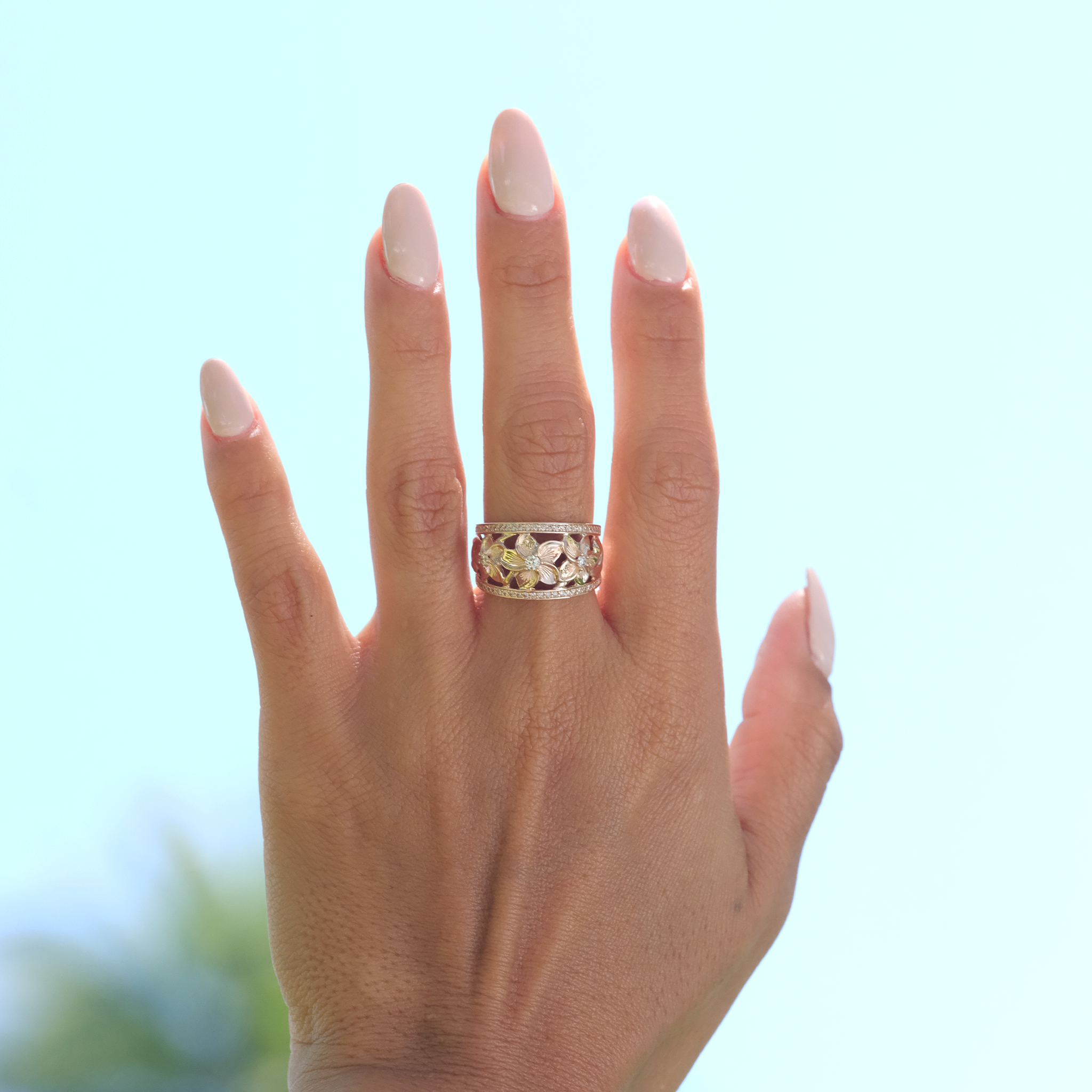 A womanʻs hand wearing a Hawaiian Heirloom Plumeria Ring in Rose Gold with Diamonds -13mm - Maui Divers Jewelry