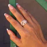 A woman's hand wearing a Hawaiian Heirloom Plumeria Engagement Ring in Rose Gold with Diamonds - 12mm - Maui Divers Jewelry
