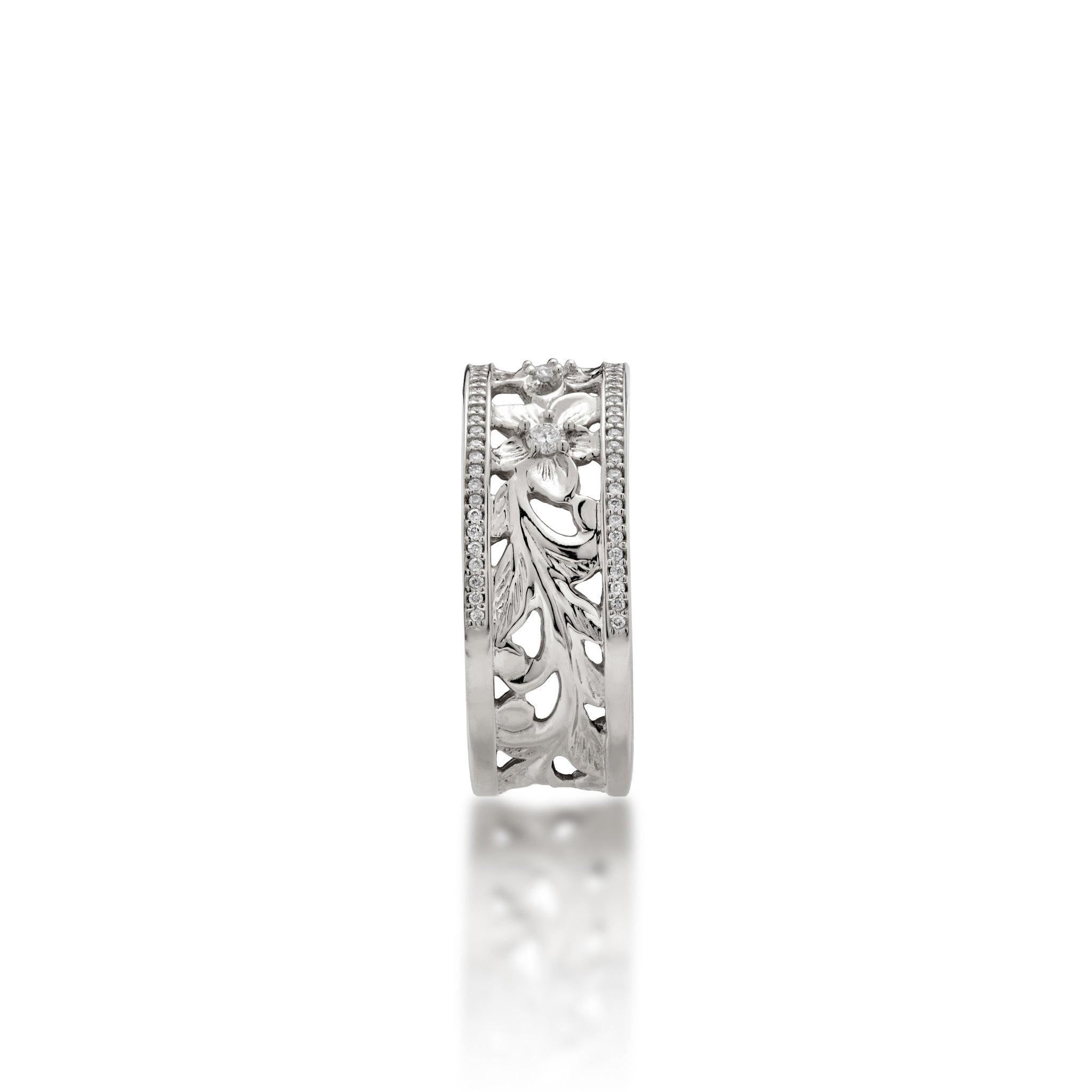 A side view of a 14k white gold Hawaiian Heirloom Ring ring diamond-accented plumeria flowers at the top and fern and maile leaf scrollwork at the bottom and a row of pave set diamonds on each side of the band, shown on a white background
