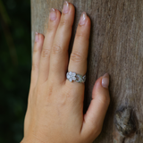 A woman's hand with a Hawaiian Heirloom Plumeria Ring in White Gold with Diamonds touching a tree - Maui Divers Jewelry