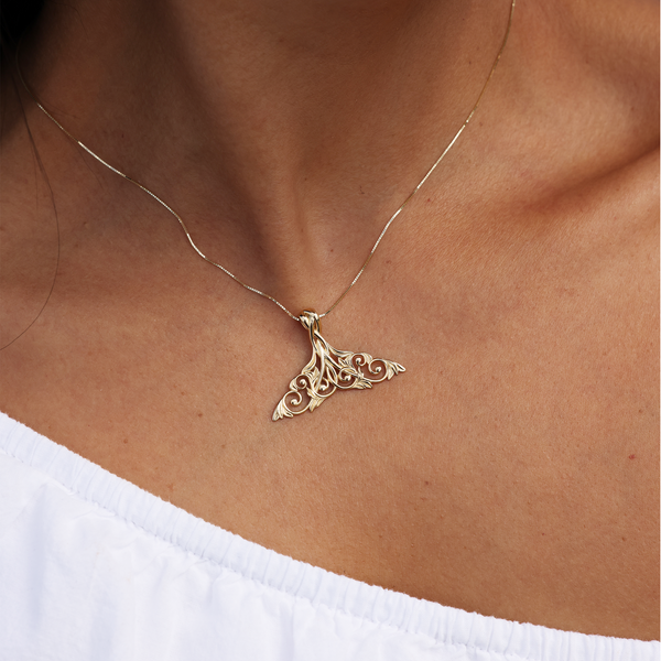 A woman's chest with a Living Heirloom Whale Tail Pendant in Gold - 35mm - Maui Divers Jewelry