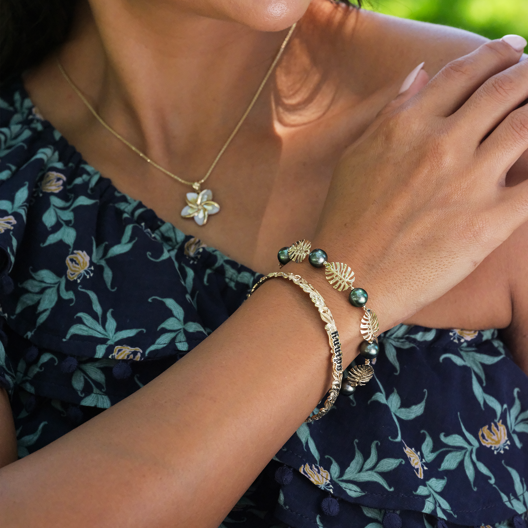 A woman's arm with a Hawaiian Heirloom Kuuipo (Sweetheart) Plumeria Enamel Bracelet in Gold - 6mm - Maui Divers Jewelry 