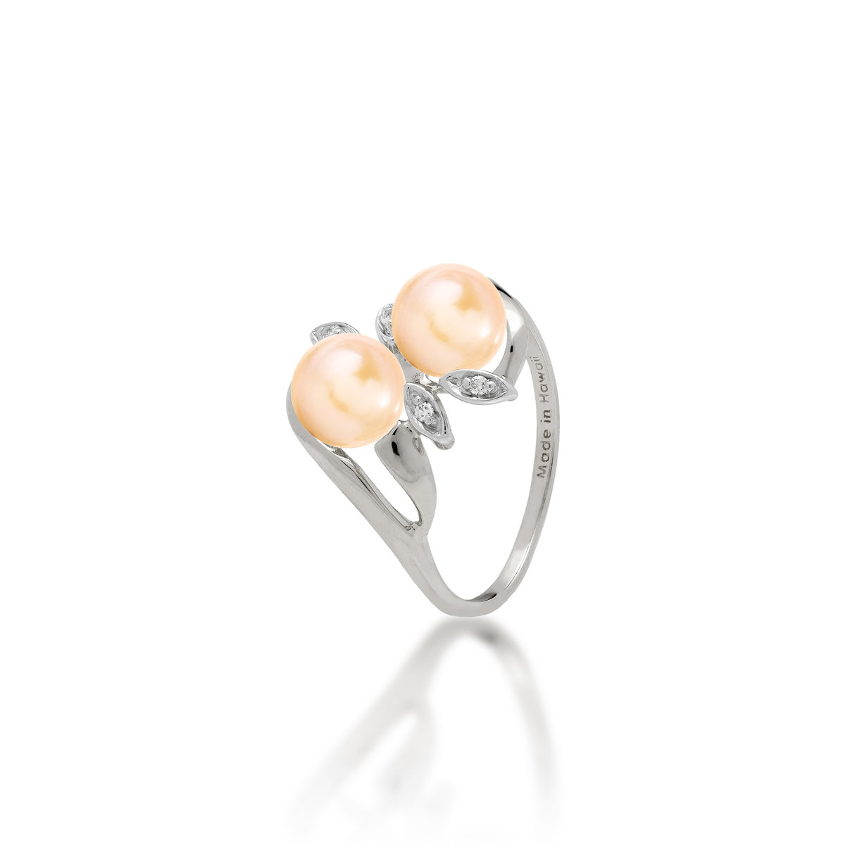 A 14k white gold ring with two peach freshwater pearls and two diamond accent maile leaves on each side, shown on white background
