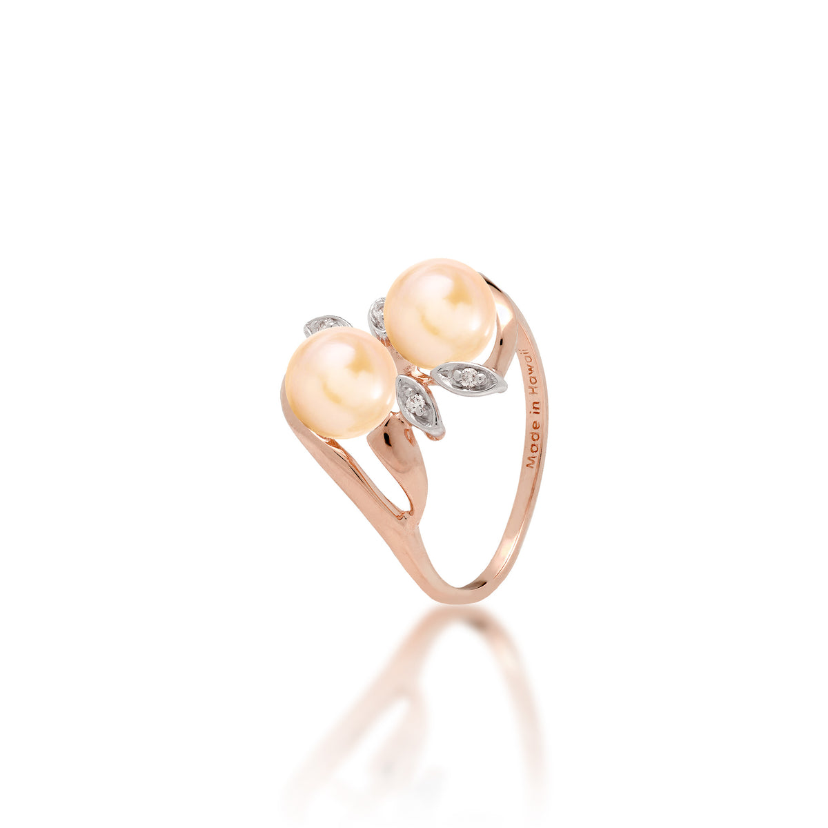 A 14k rose gold ring with two peach freshwater pearls and two diamond accent maile leaves on each side, shown on white background