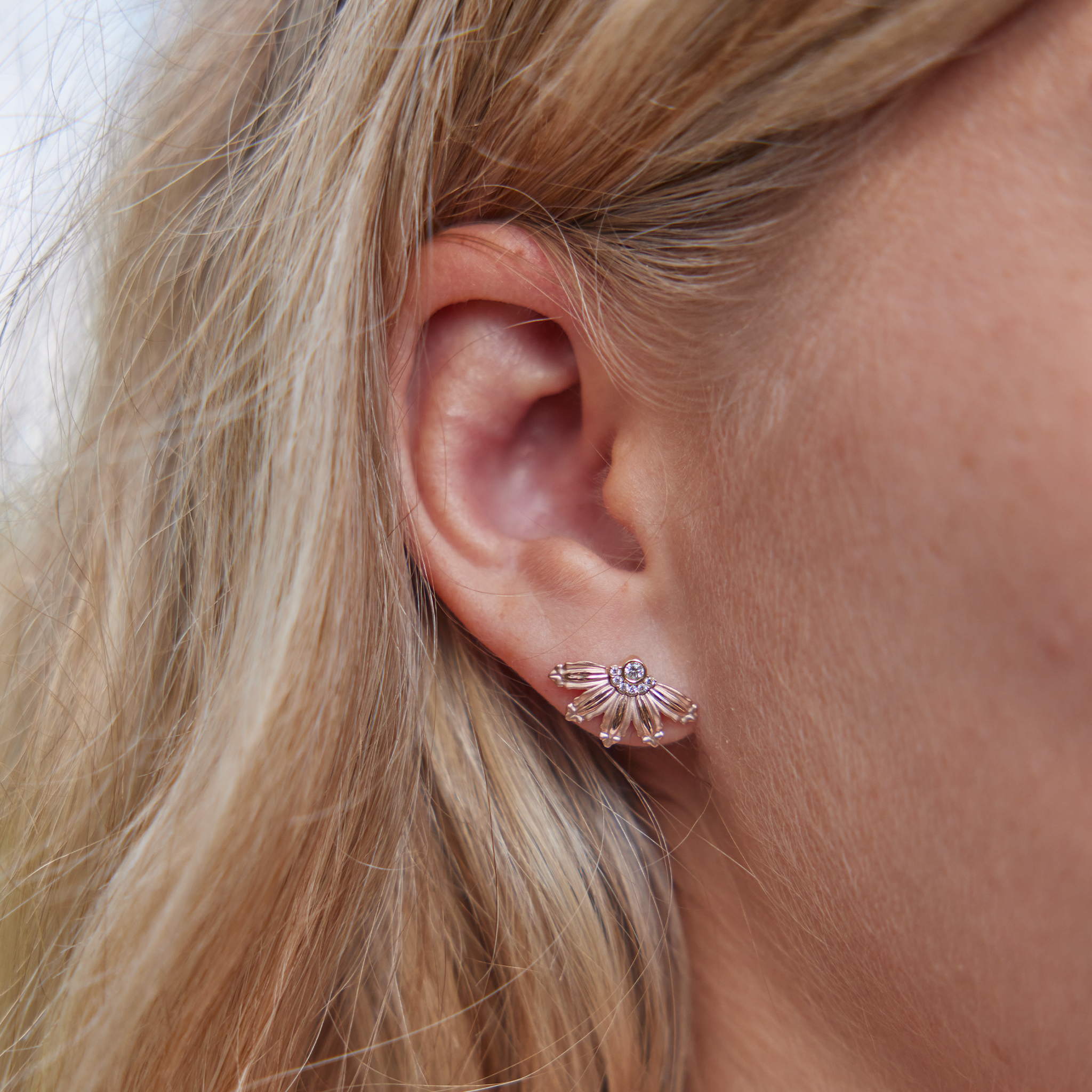 Close up of ear wearing Mountain Naupaka Earrings in Two Tone Gold with Diamonds