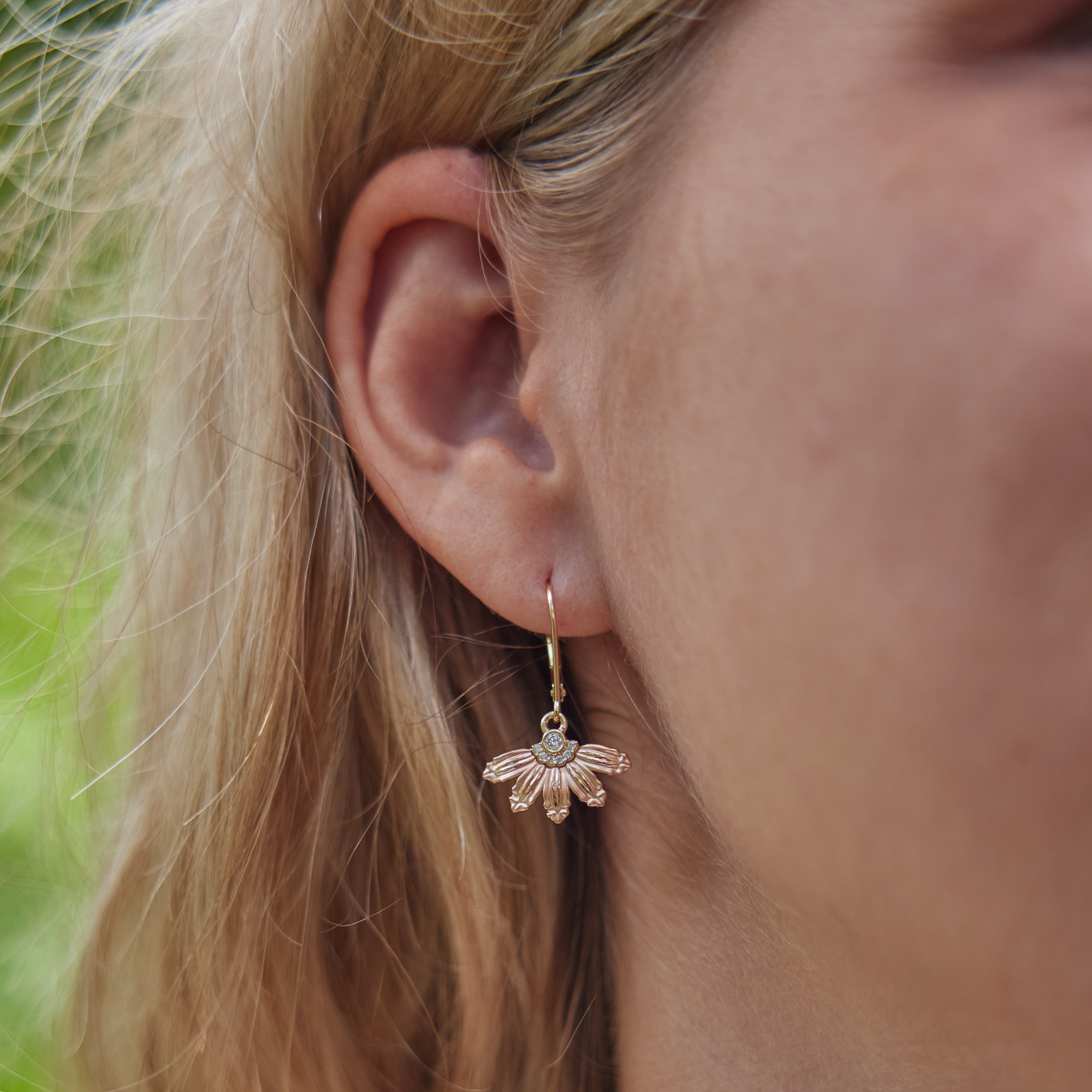 Close up of woman's ear wearing Mountain Naupaka Earrings in Two Tone Gold with Diamonds
