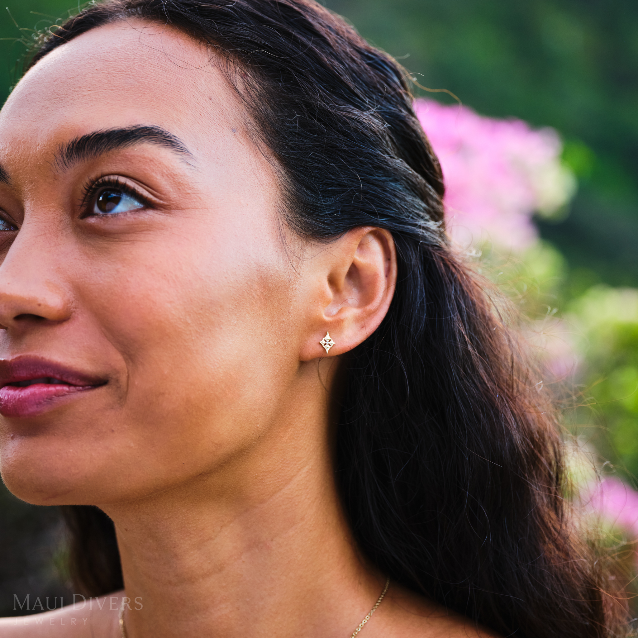 Close-up of a woman wearing 10mm Hawaiian Quilted Star Earrings in 14k Yellow Gold with Diamonds