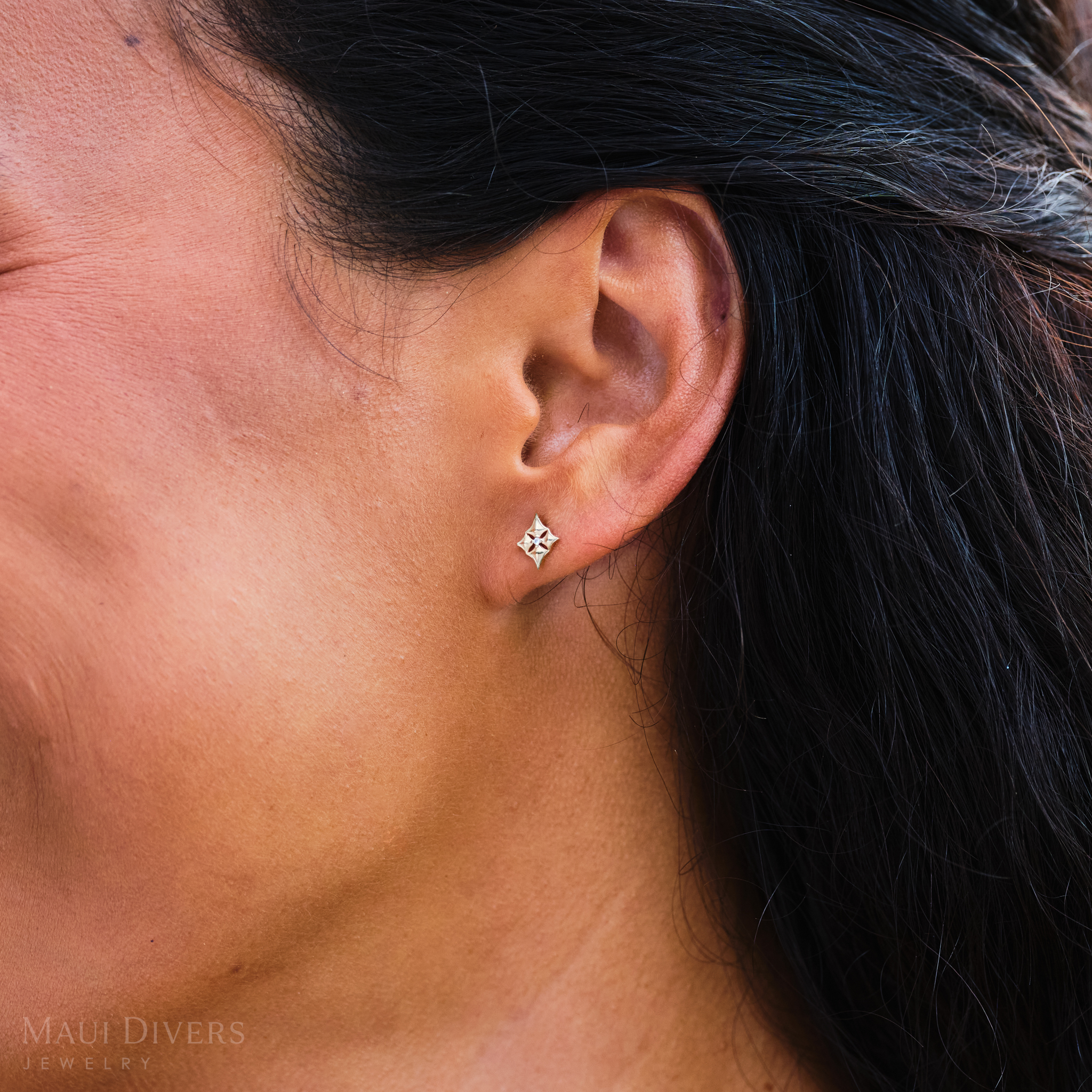 Close up of 10mm Hawaiian Quilted Star Earrings in 14k Yellow Gold with Diamonds on ear