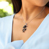 Close up of Honu Black Coral Pendant in White Gold - 37mm on Neckline with blue dress