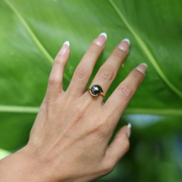 Woman wearing Tahitian Black Pearl Ring in Gold - 12-13mm on hand touching leaf