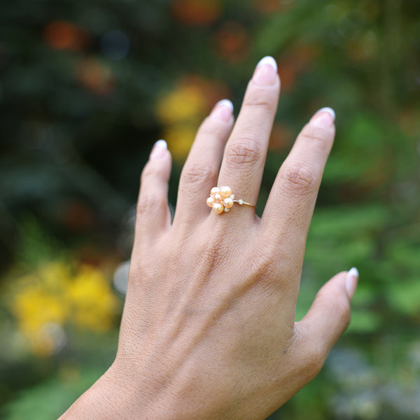 Woman wearing Tiny Bubbles Peach Freshwater Pearl Ring in Gold with Diamonds with forest background