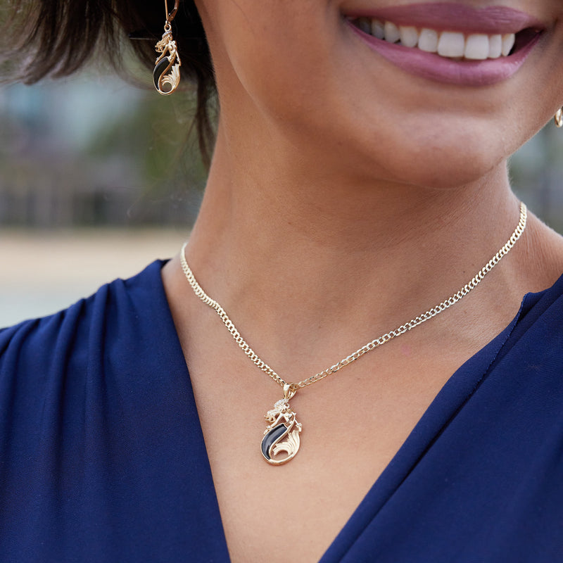 A woman wearing a Sealife Mermaid Black Coral Pendant in Gold with Diamonds - 30mm and earrings - Maui Divers Jewelry