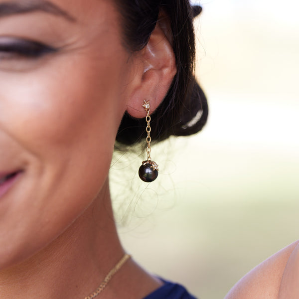A woman's ear with with Reefs Starfish Tahitian Black Pearl Earrings in Gold with Diamonds - 10-11mm - Maui Divers Jewelry