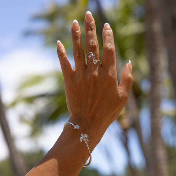 a woman's hand with the Maui Divers Jewelry Honu and Plumeria Ring in Sterling Silver on it.