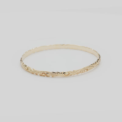 Video of the 4.5mm Hawaiian Heirloom Old English Scroll Bracelet in Gold turning on a white background