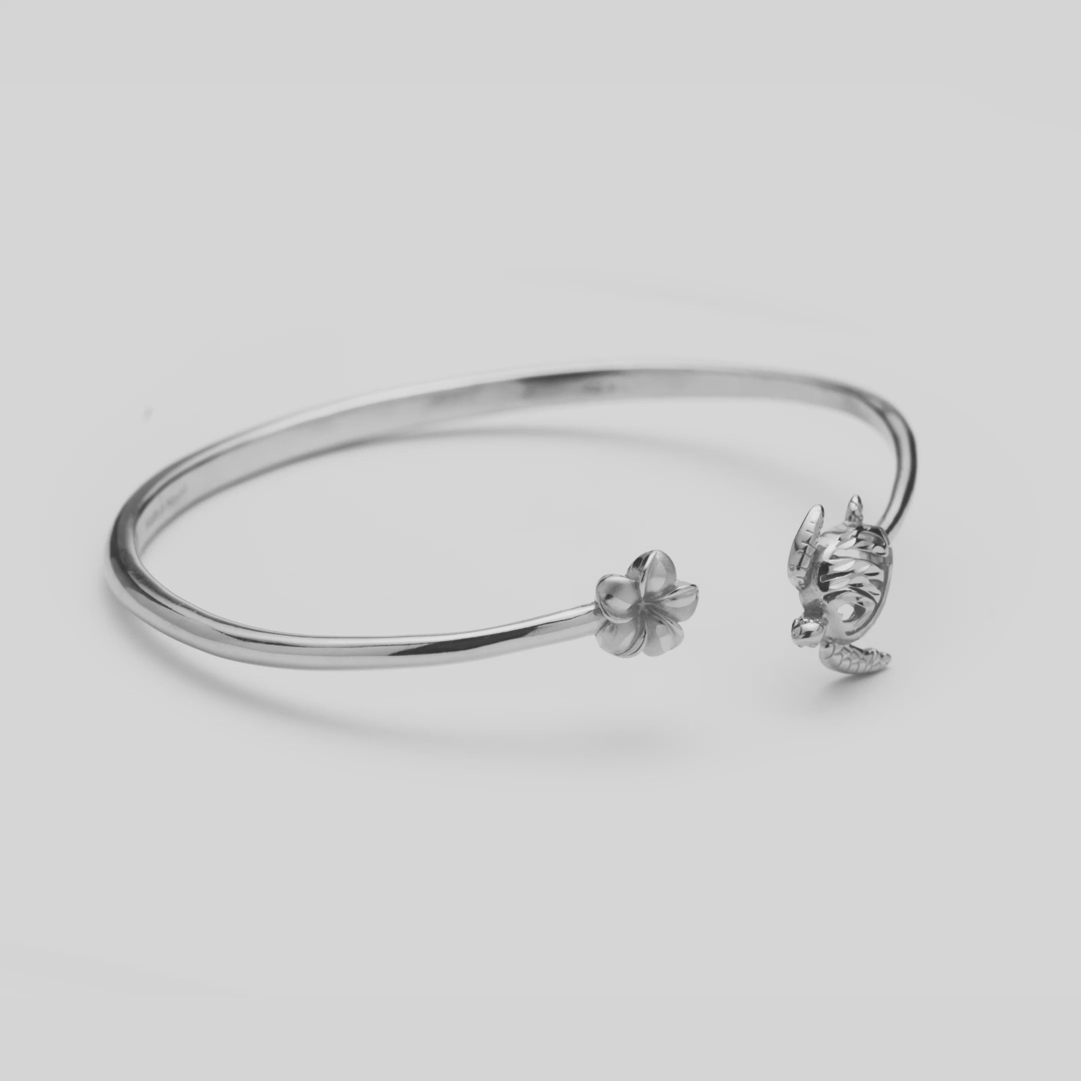 Video of the Honu and Plumeria Bracelet in Sterling Silver turning on a white background
