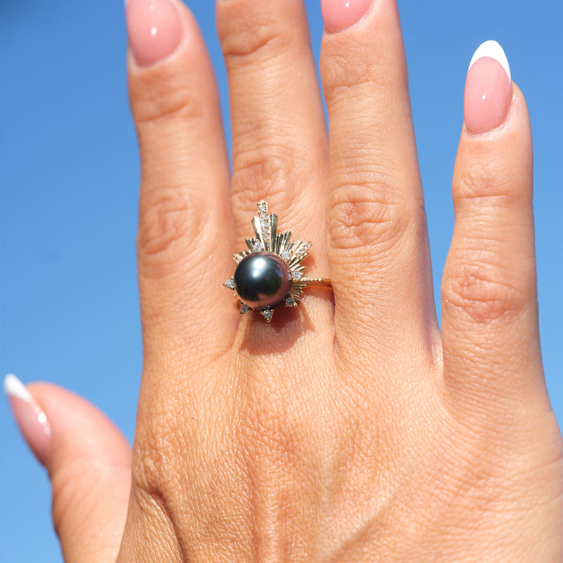 A woman's hand wearing a E Hoʻāla Tahitian Black Pearl Ring in Gold with Diamonds - 21mm - Maui Divers Jewelry